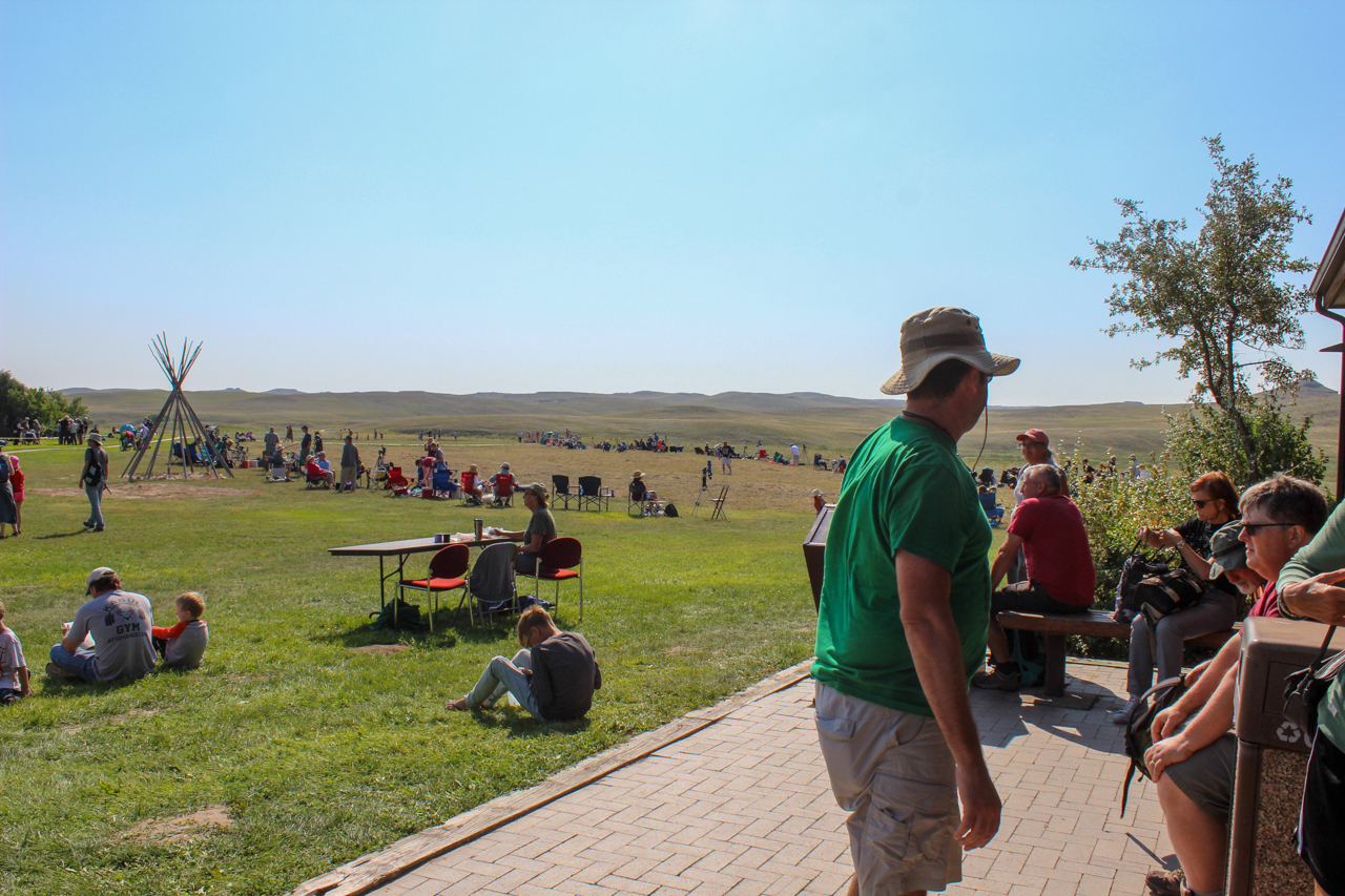Large crowd of visitors scattered across a patio and grassy areas.