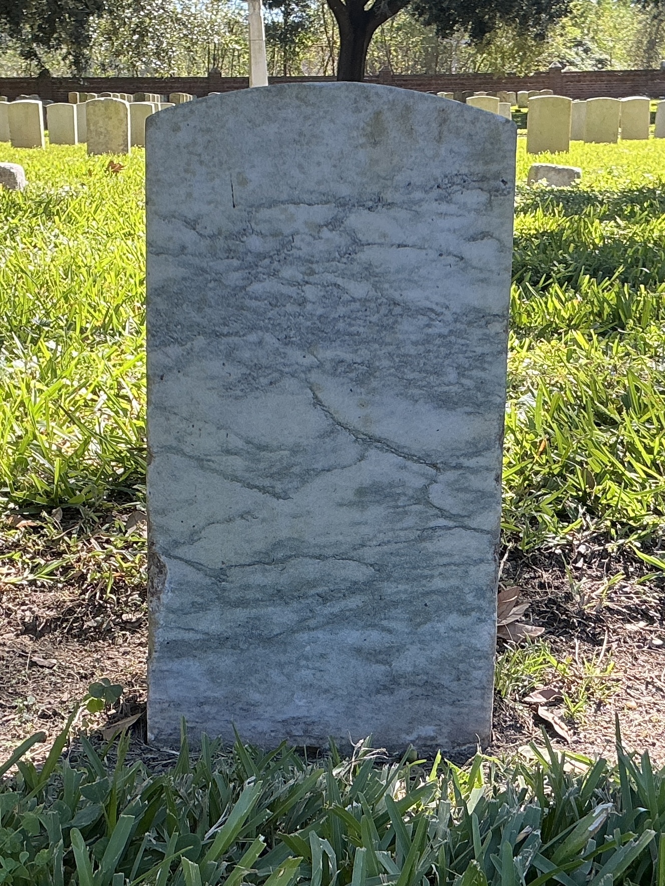 Back of historic upright marble headstone with recessed shield face.