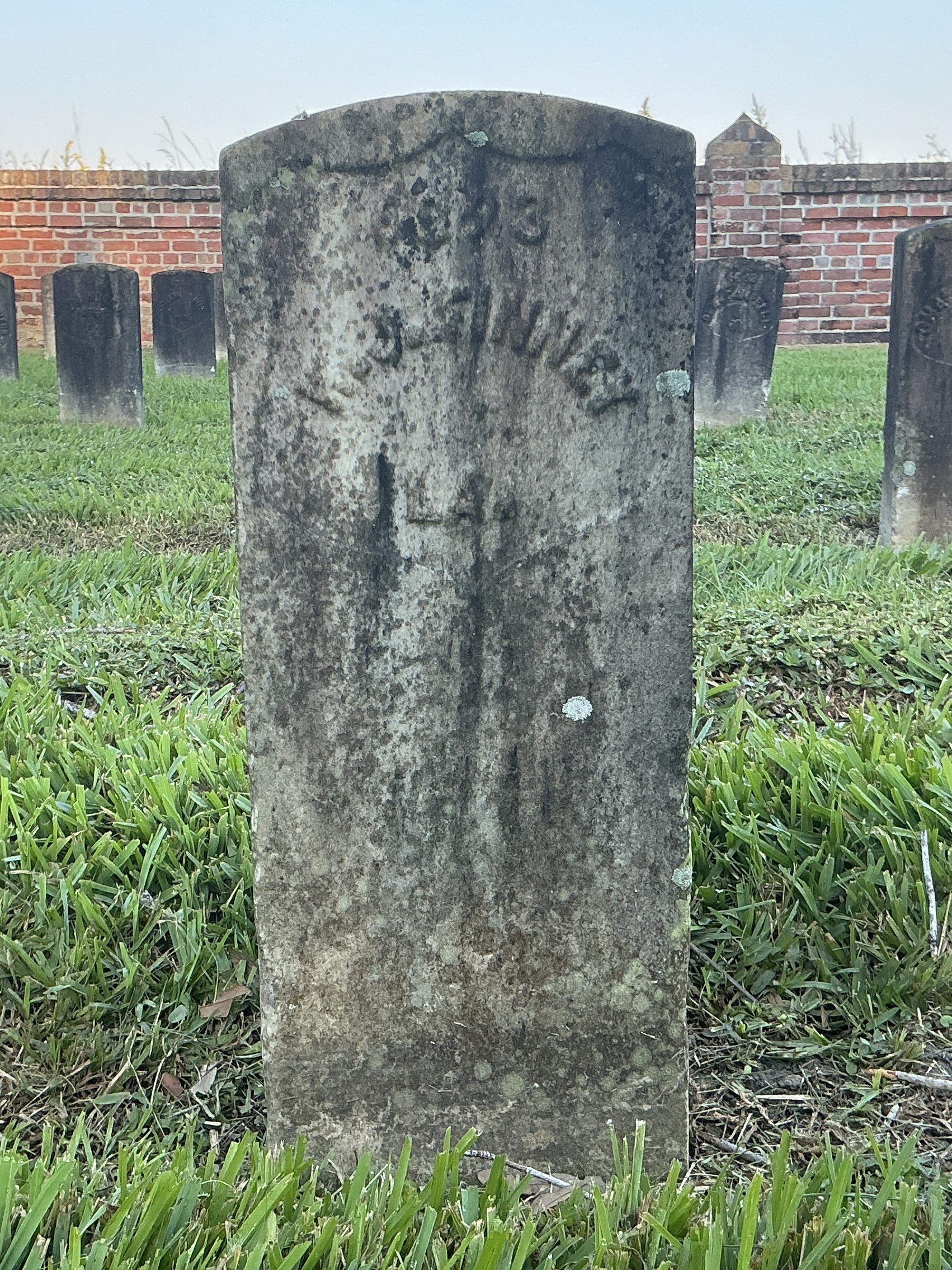 Front of historic upright marble headstone with recessed shield face.