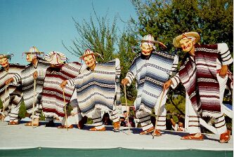 Folklórico dancers at La Fiesta de Tumacácori, kids in costumes, masks, and holding canes like old men