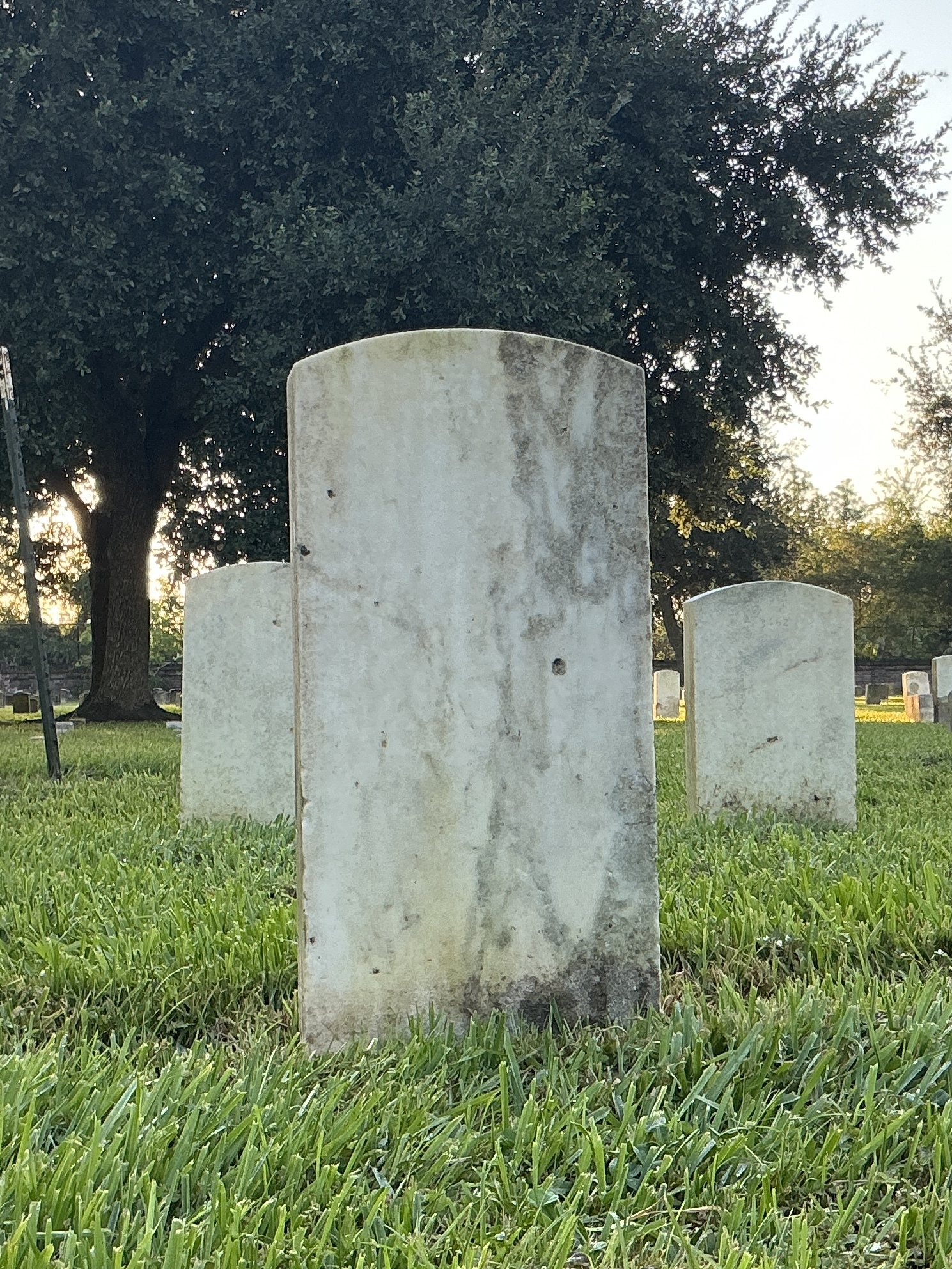 Back of historic upright marble headstone with recessed shield face.