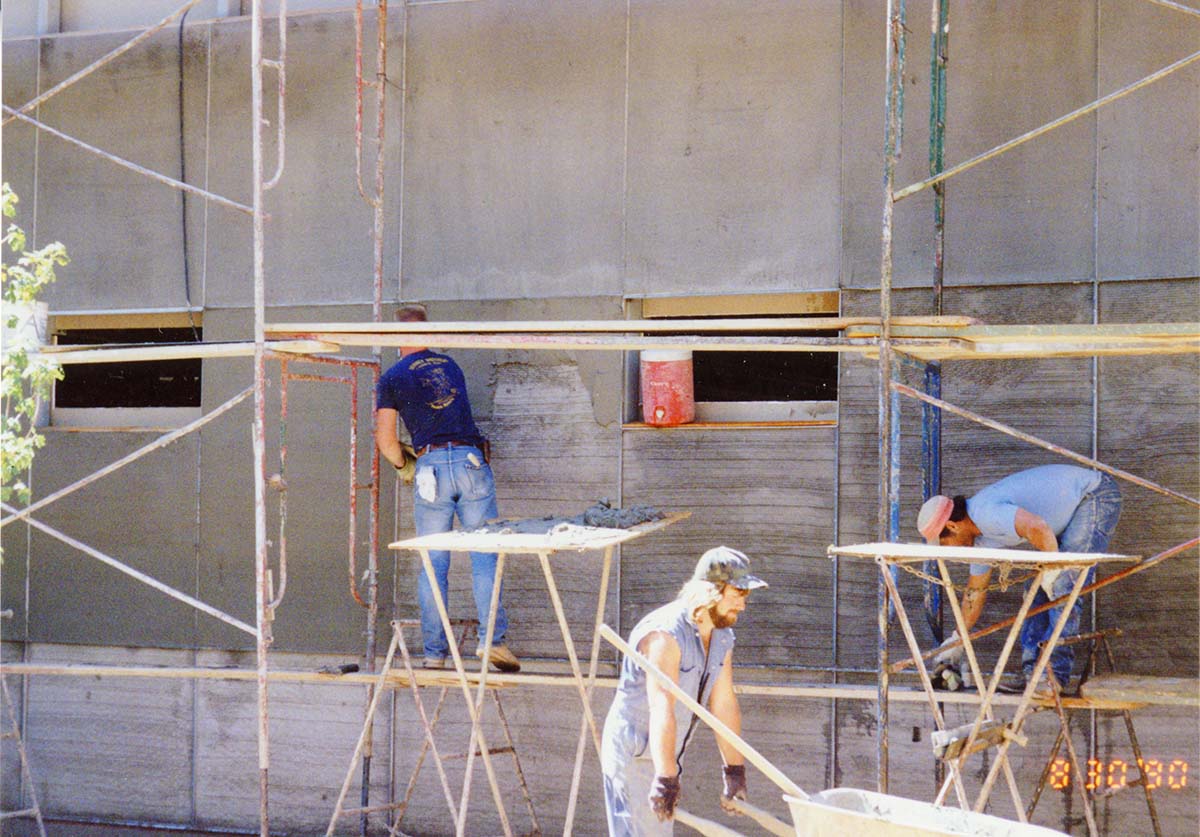 Men working on the outside wall during construction of headquarters addition.