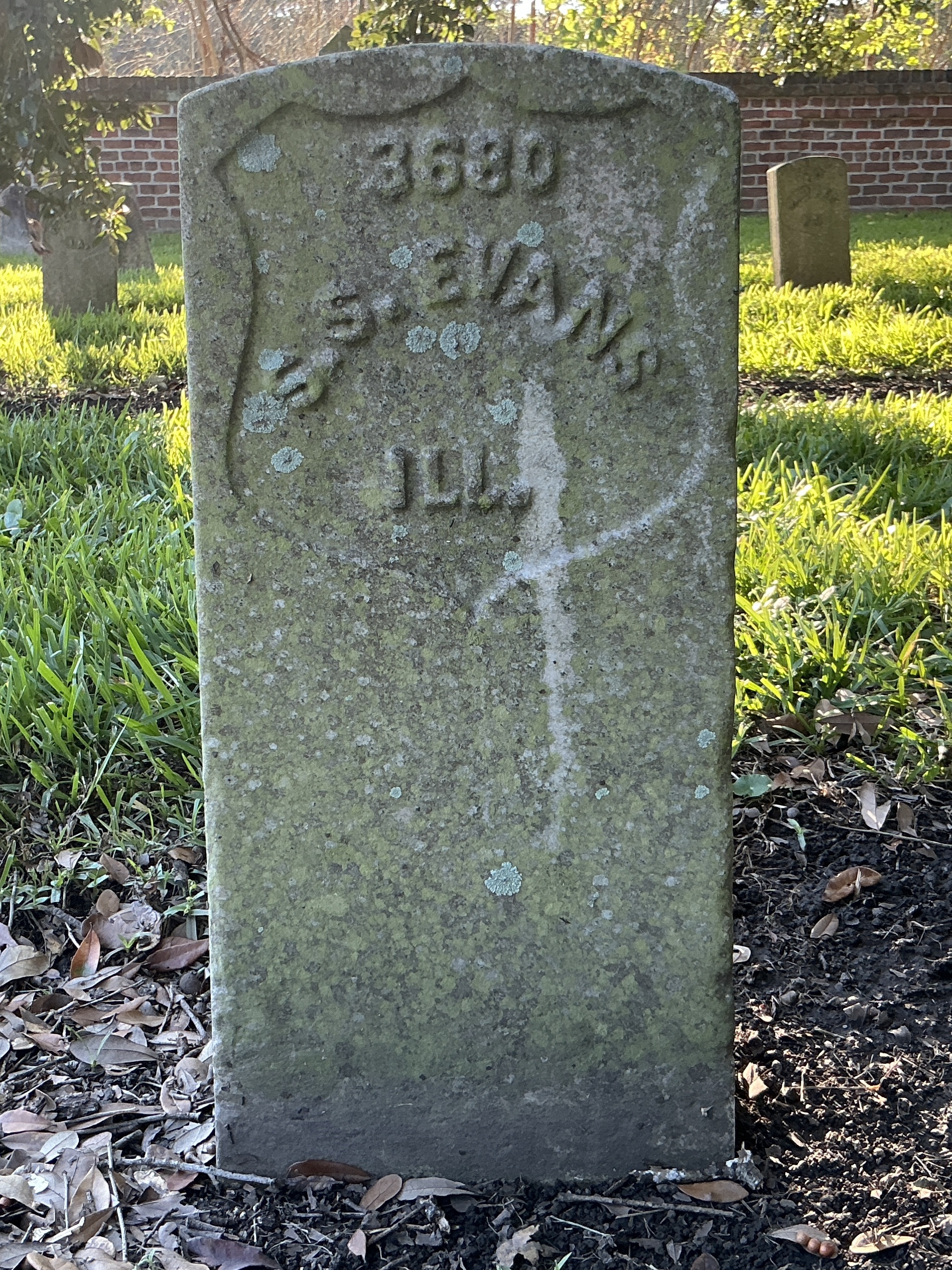 Front of historic upright marble headstone with recessed shield with recessed lettering face.