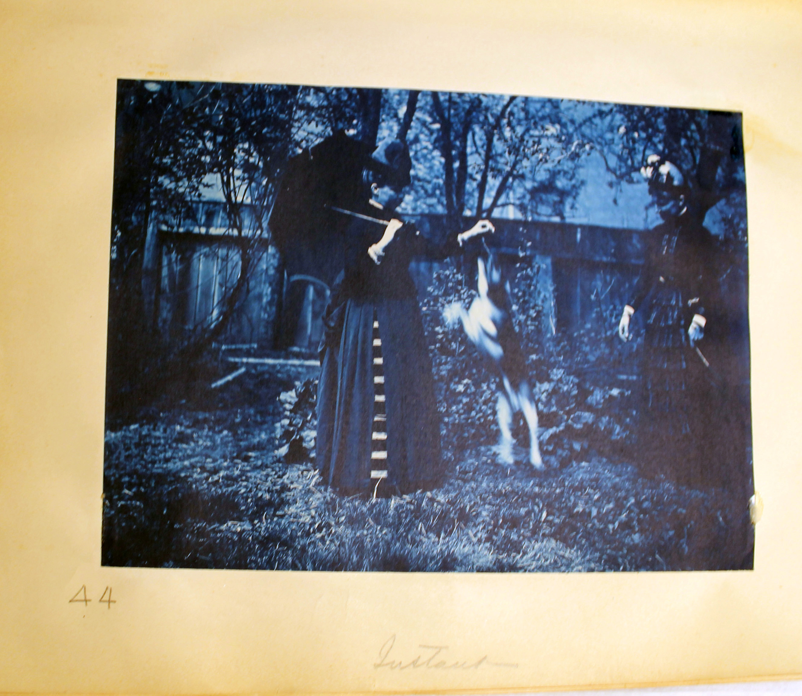 Blue toned photo of two Longfellow family members playing with dog.