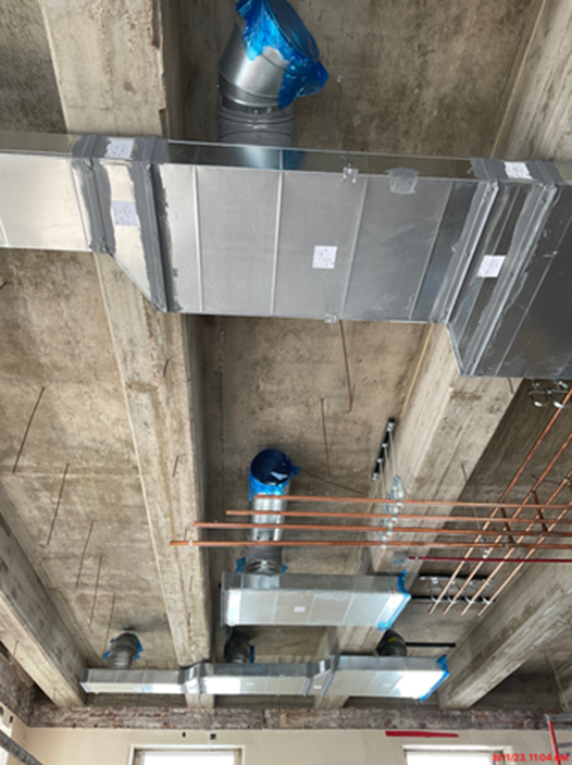 Duct work and cooper pipes running along the ceiling as part of the new HVAC installation.