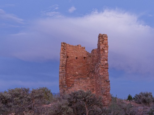 Sandstone structure standing alone at dusk surrounded by sagebrush.