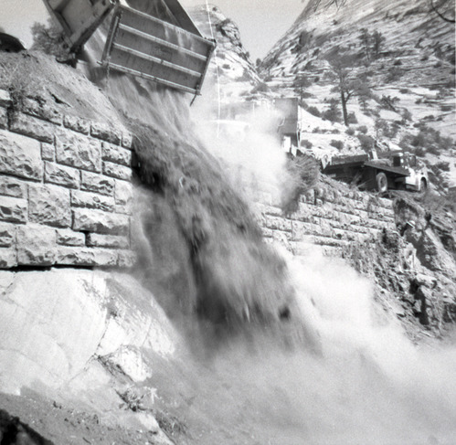 Dump truck dumping dirt during retaining wall repairs along East Rim road.