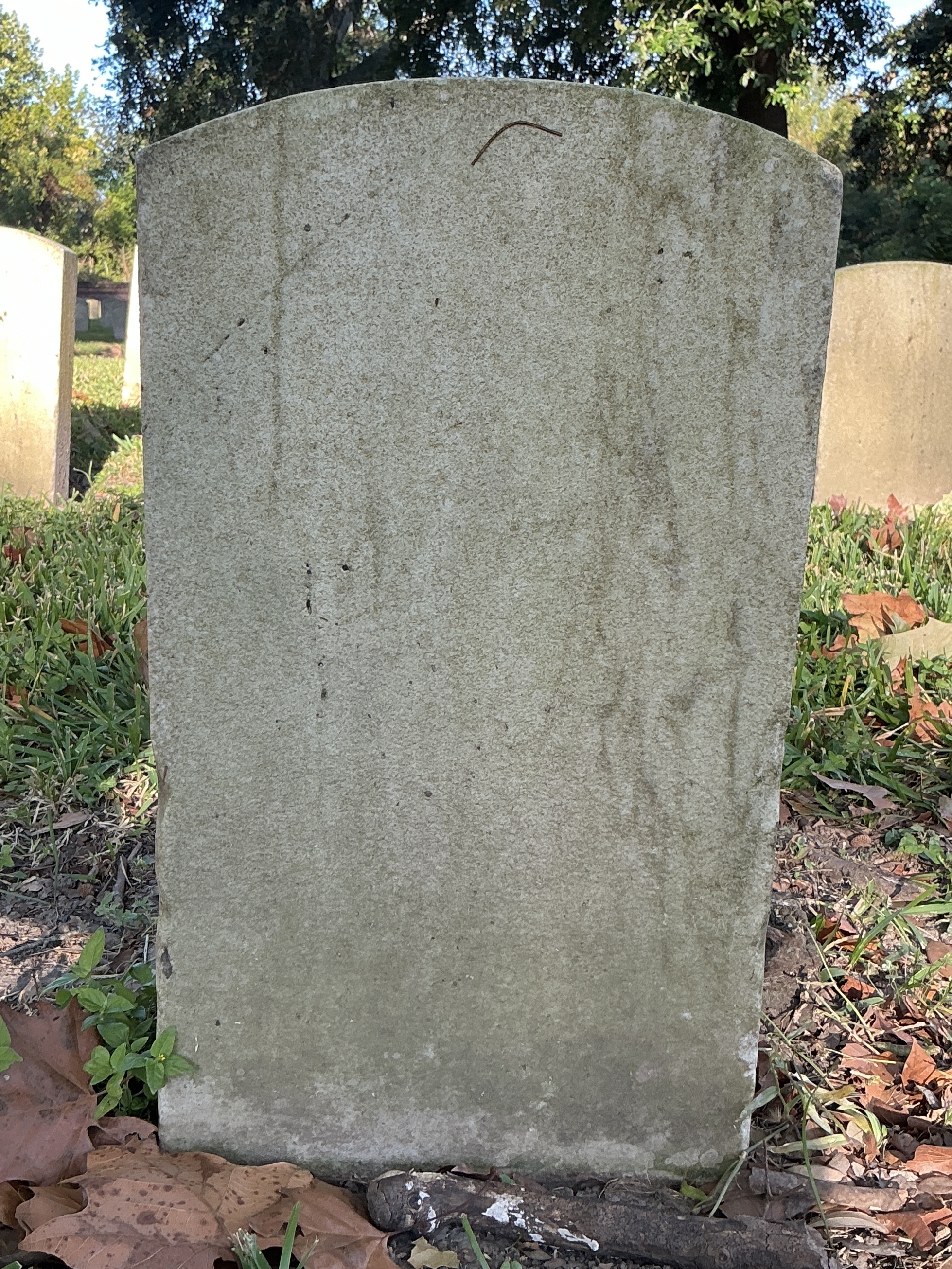 Back of historic upright marble headstone with recessed shield face.