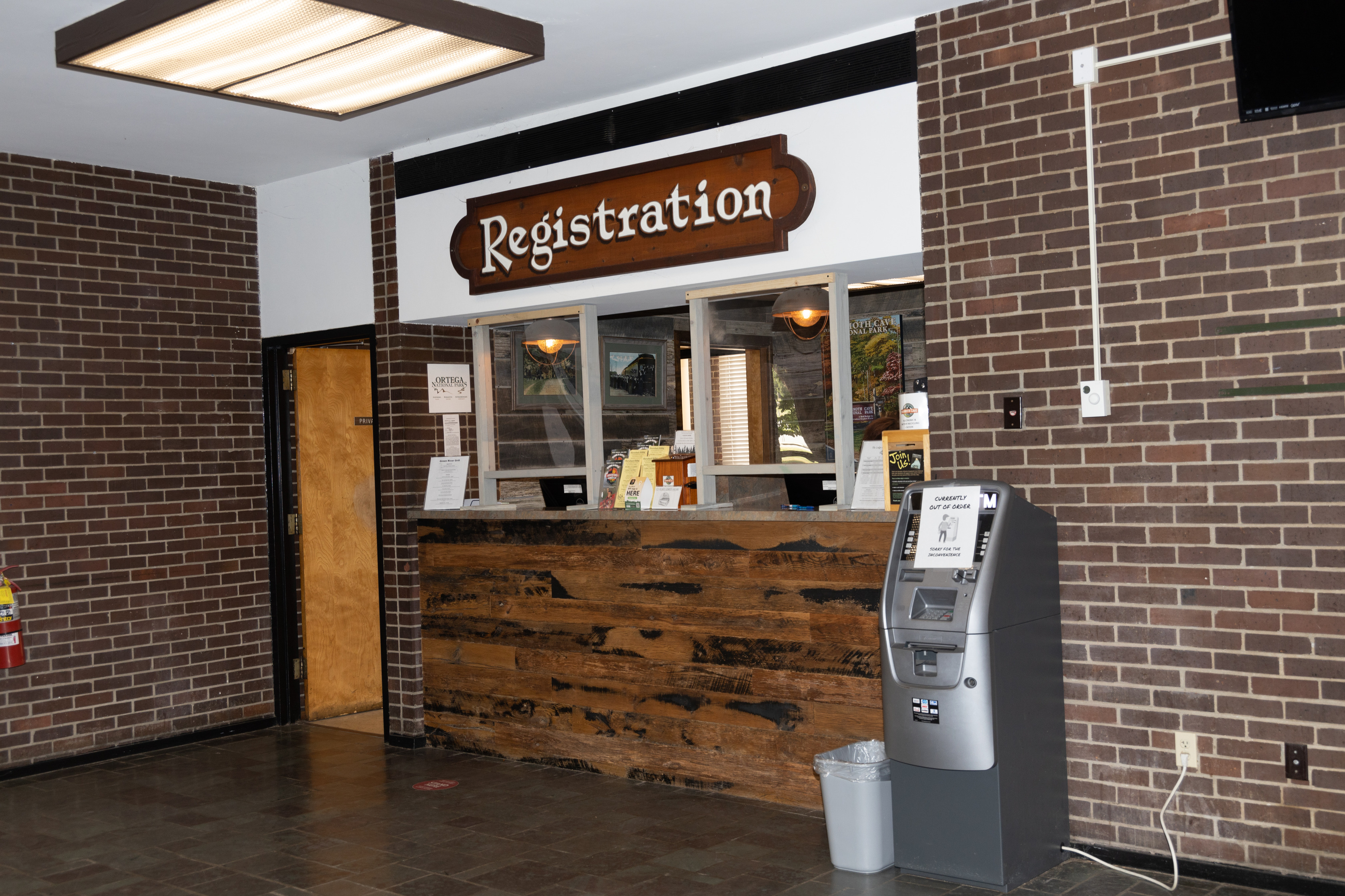 A sign reads "Registration" above a wooden desk area surrounded by brick walls. 