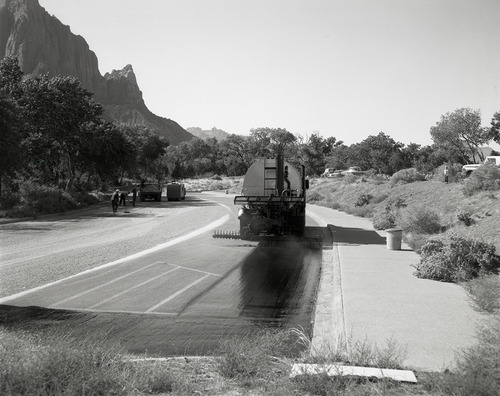 Men operating sealcoating machine while sealcoating parking area in Zion.