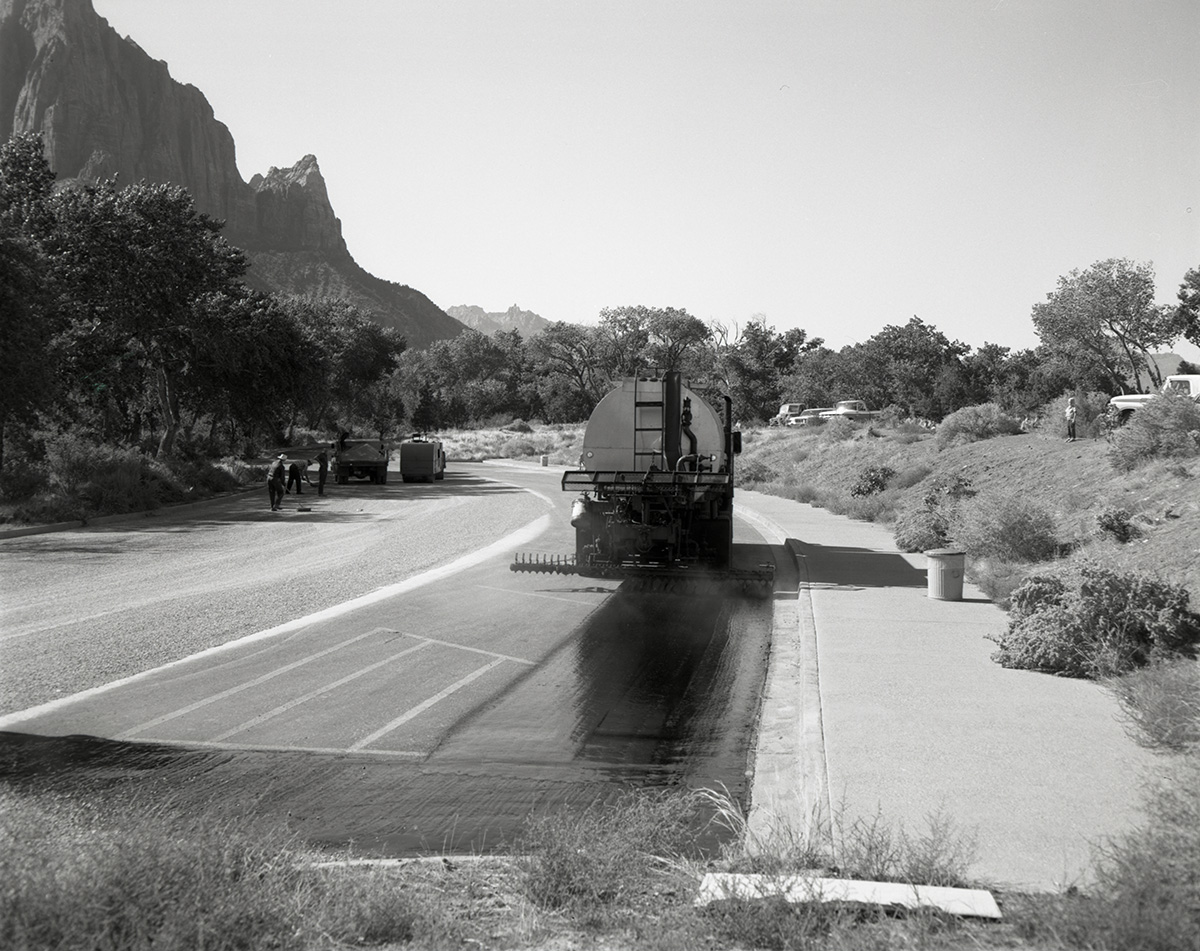 Men operating sealcoating machine while sealcoating parking area in Zion.