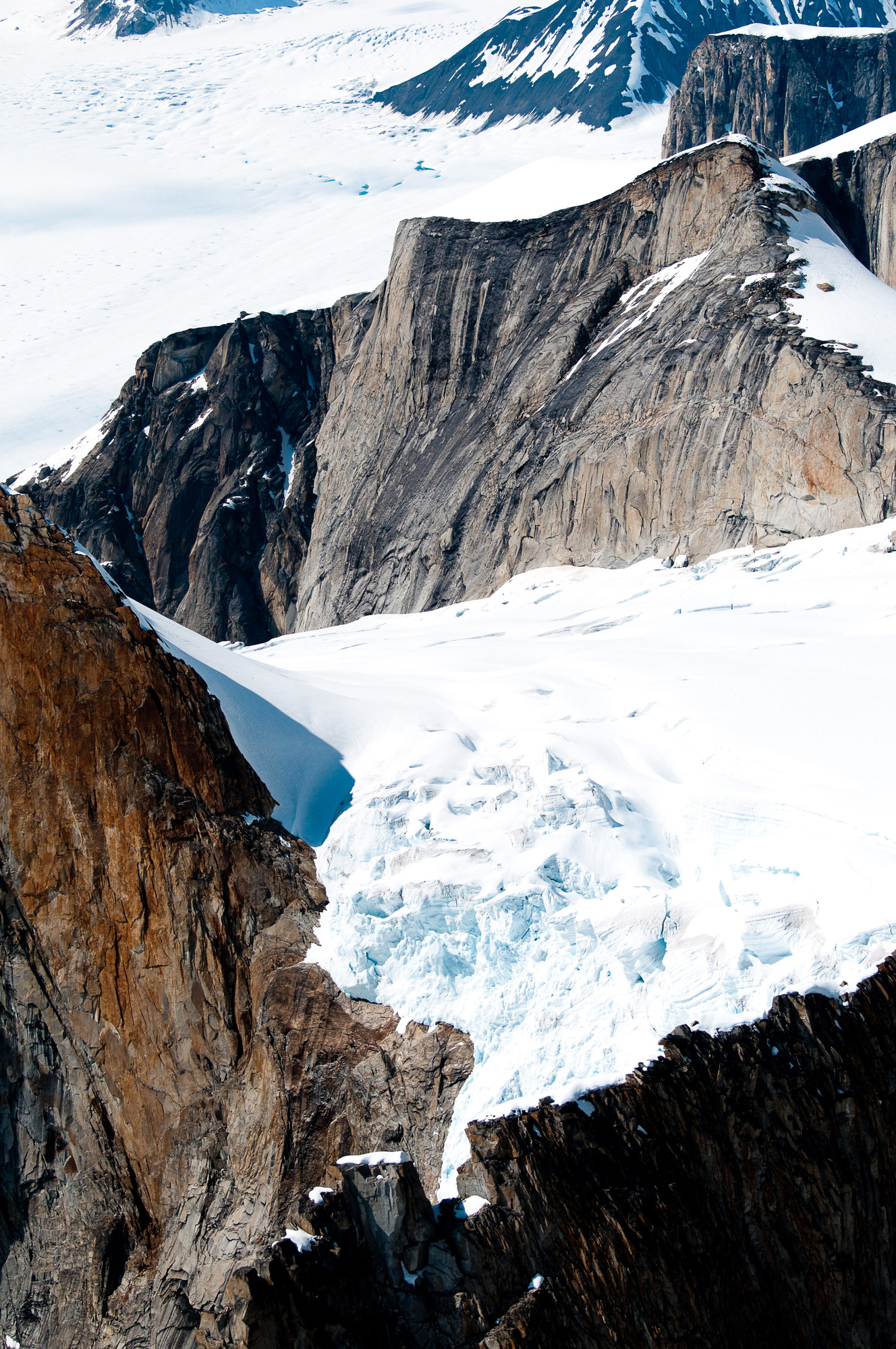 a small glacier flowing down a mountain to a much larger glacier
