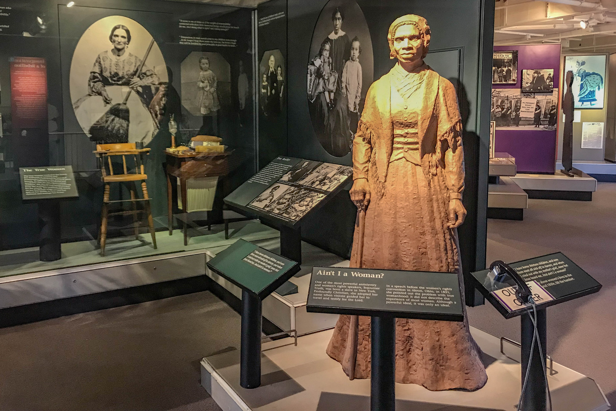 Museum exhibits with objects, statues, photographs, and panels about the women suffrage movement