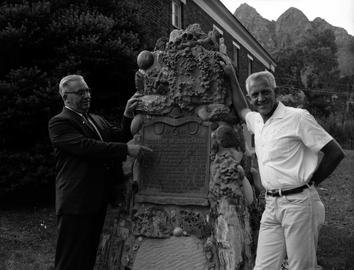 Centennial Preparation Committee members Springdale Mayor Austin Excell and Bishop Alvin Hardy pose next to 'Discovery of Zion Canyon' commemorative plaque.