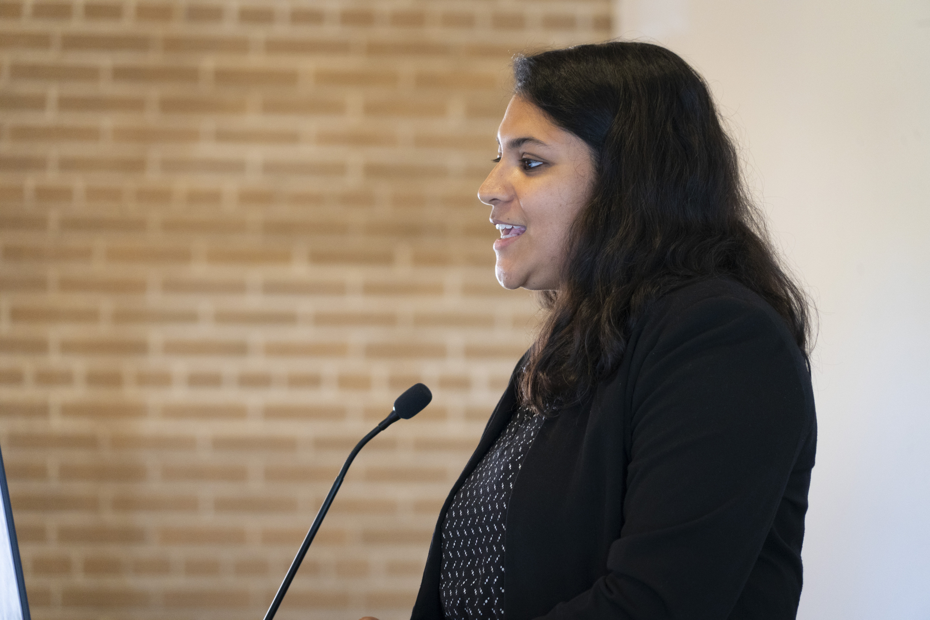 A woman in a black suit speaks to an audience.