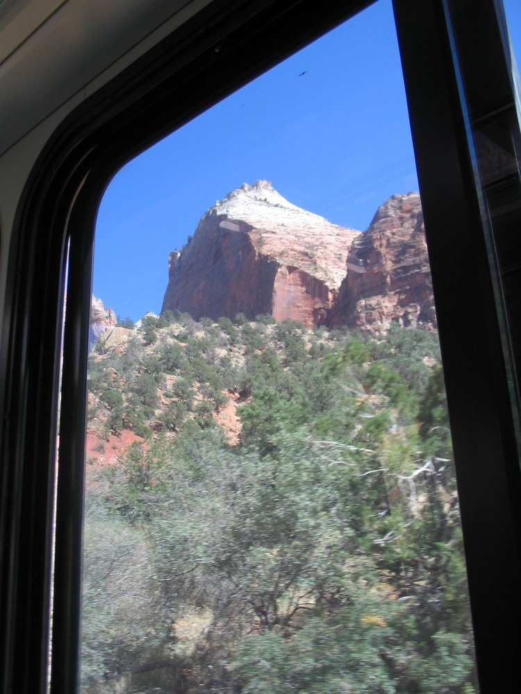 Looking out the window of the bus, you can see canyon walls. 