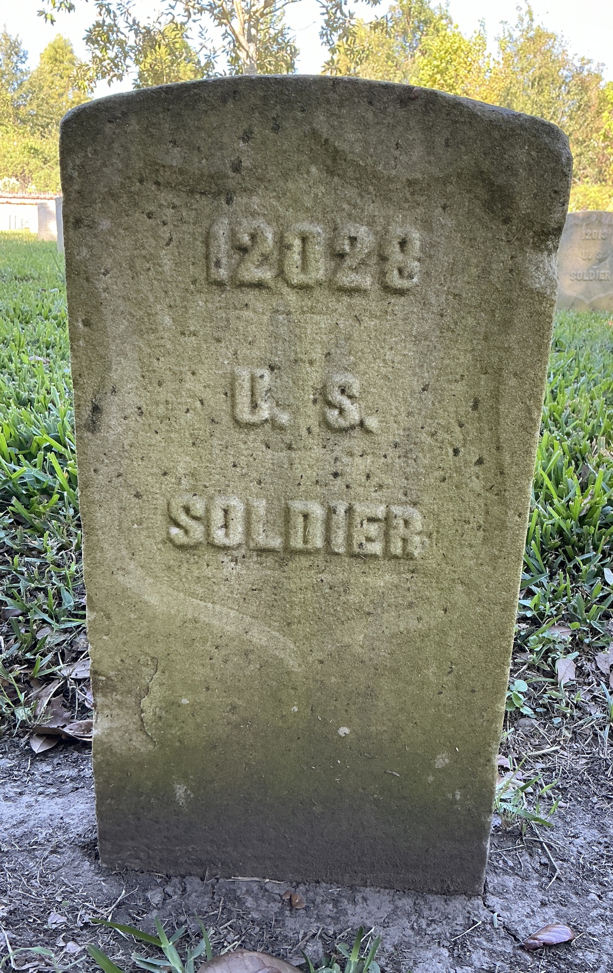 Front of historic upright marble headstone with recessed shield face.