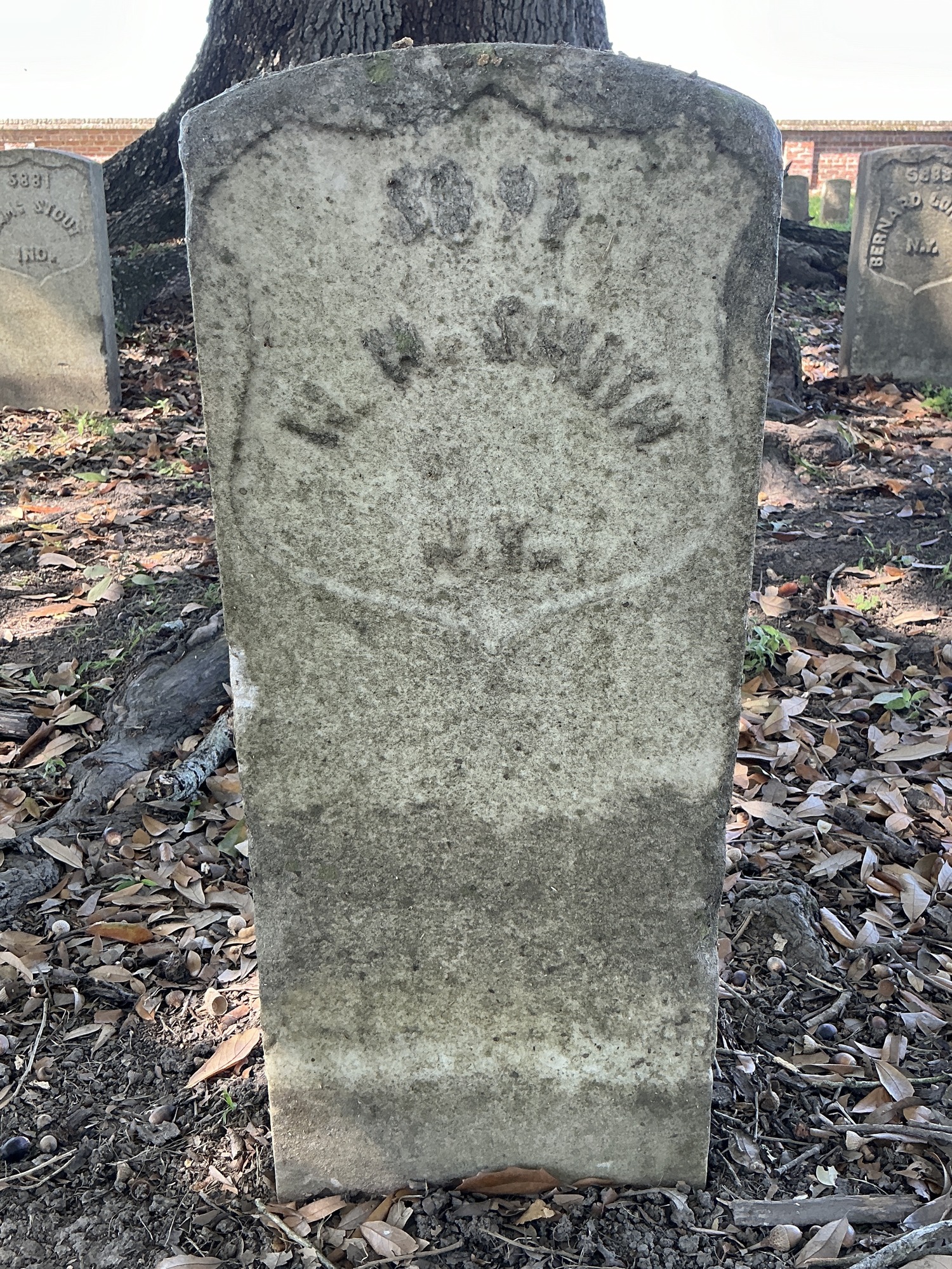 Front of historic upright marble headstone with recessed shield face.