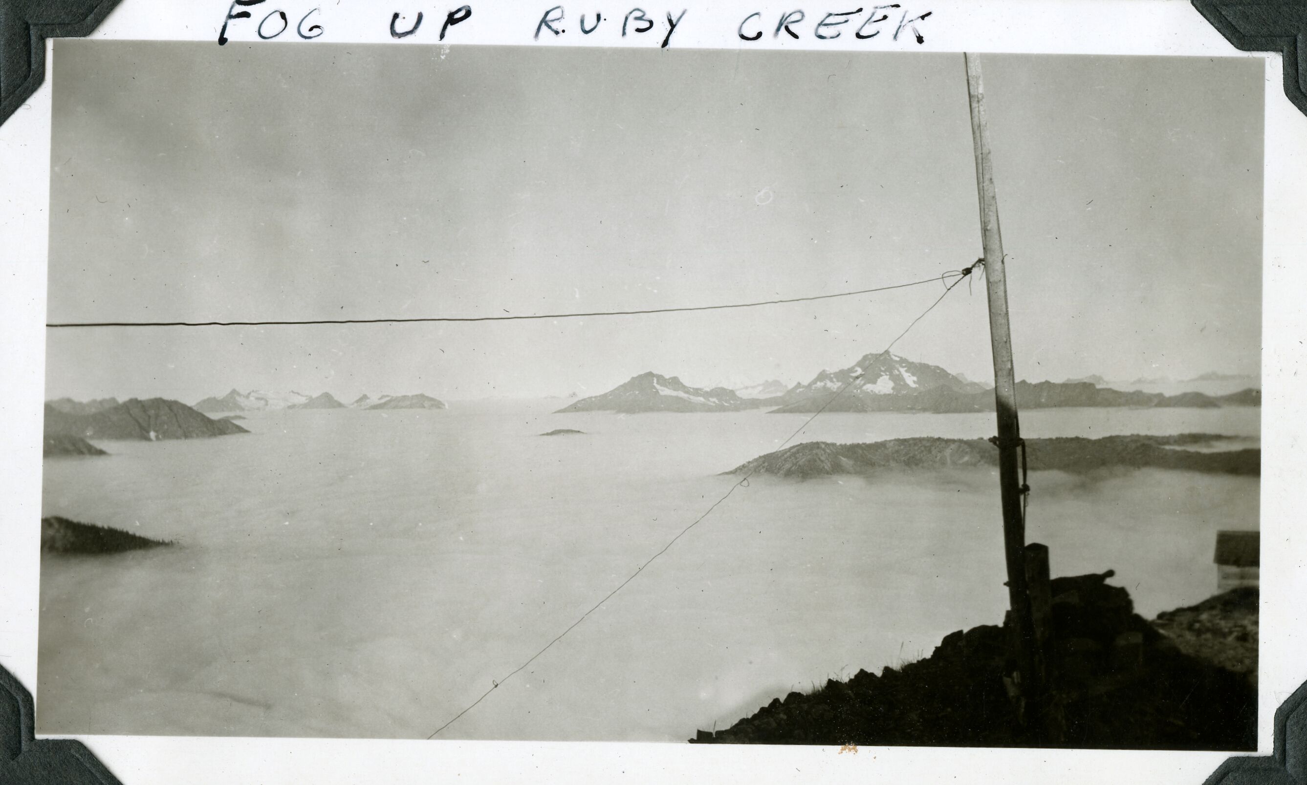 A distant view of multiple mountain peaks showing above a sea of fog.