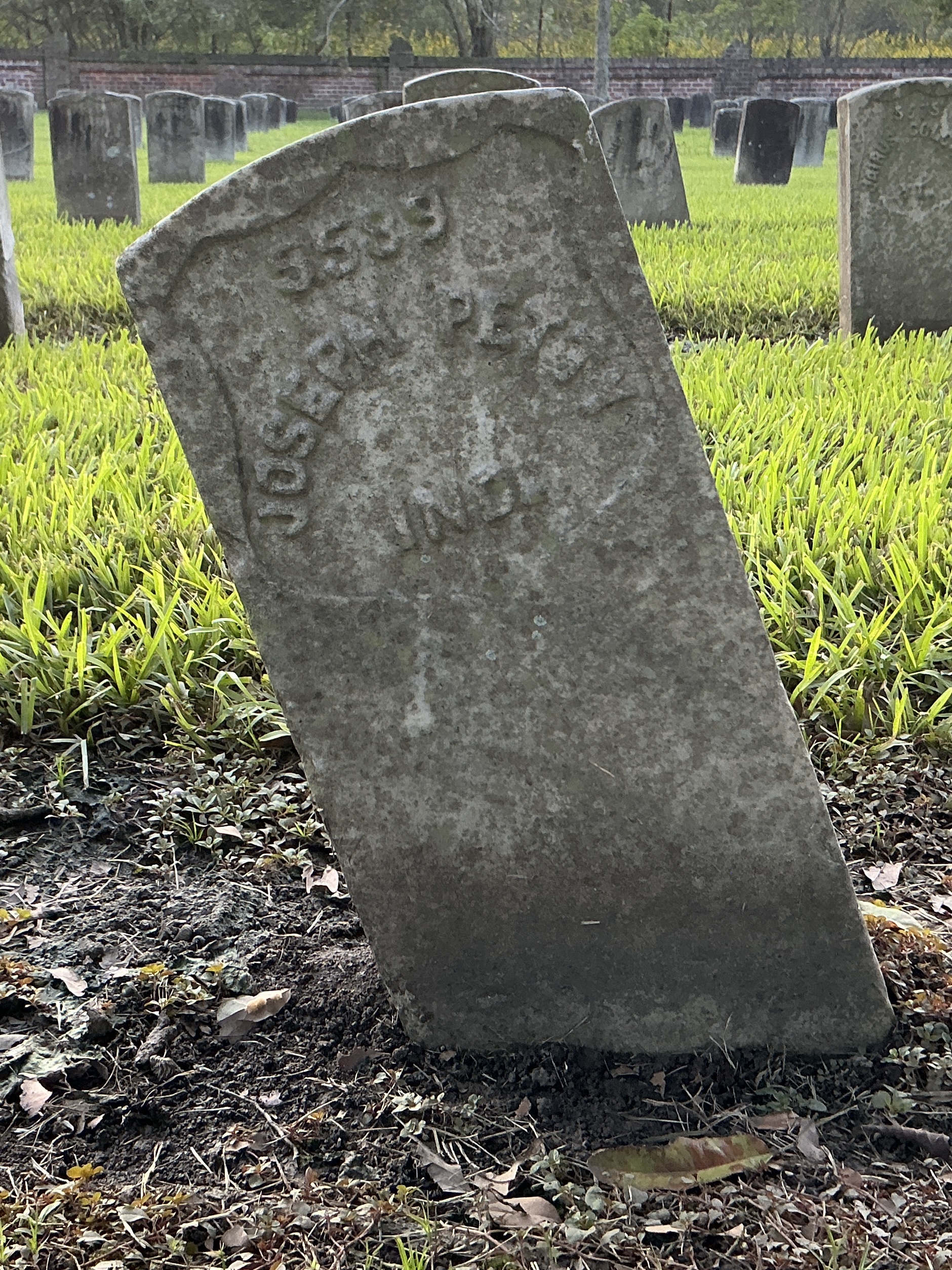 Front of historic upright marble headstone with recessed shield face.