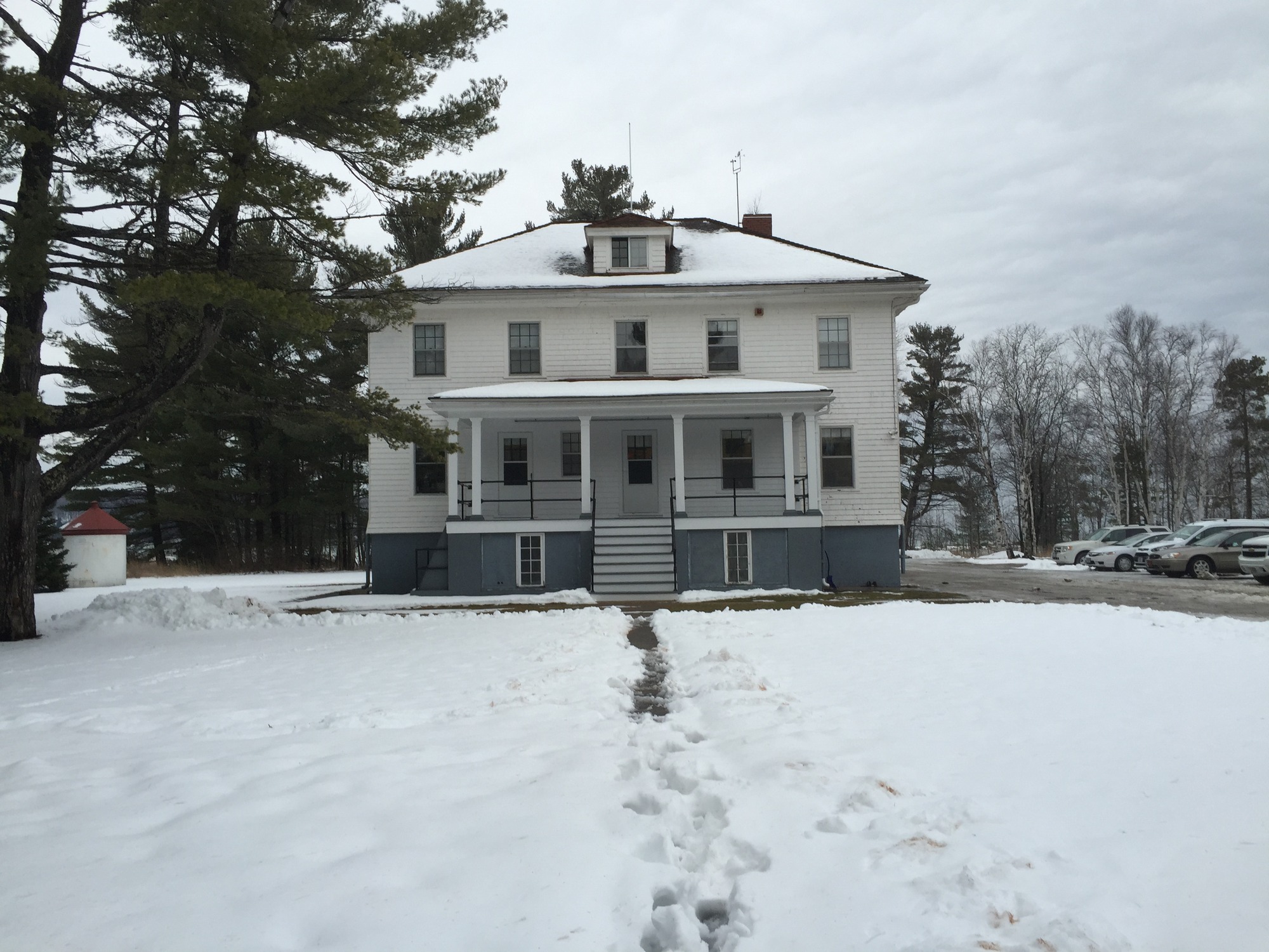 two story white wooden building surrounded by snowy yard.