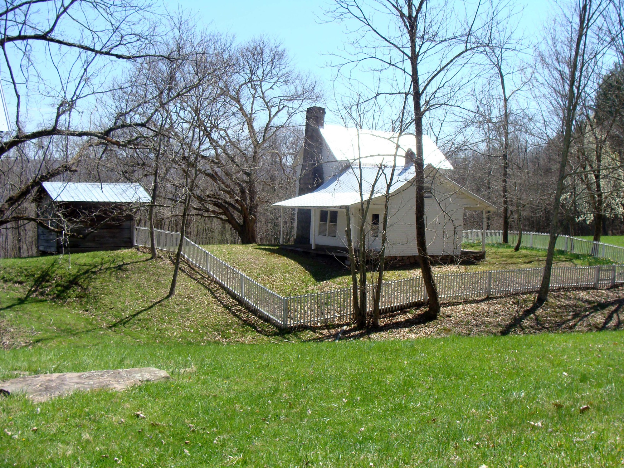old white farmhouse with picket fence and one out building