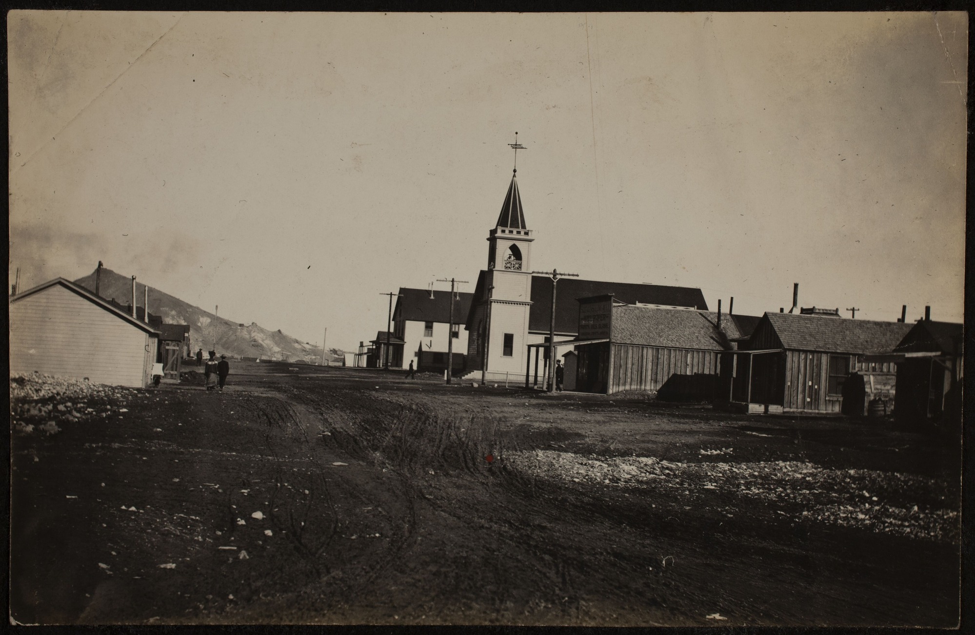 A church and town structures along a dirt road.