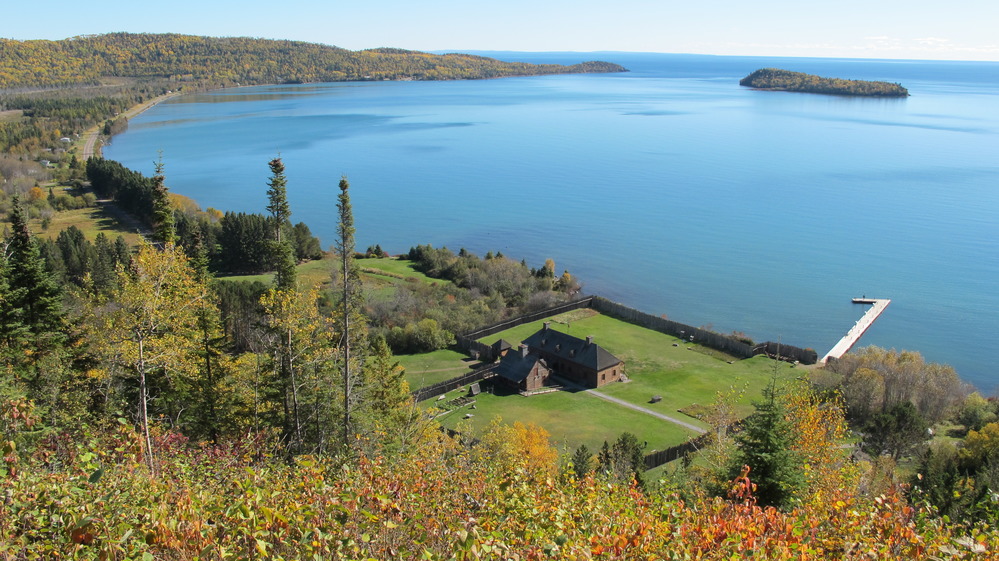 Blue lake water enclosed by Fall colored forest and an island