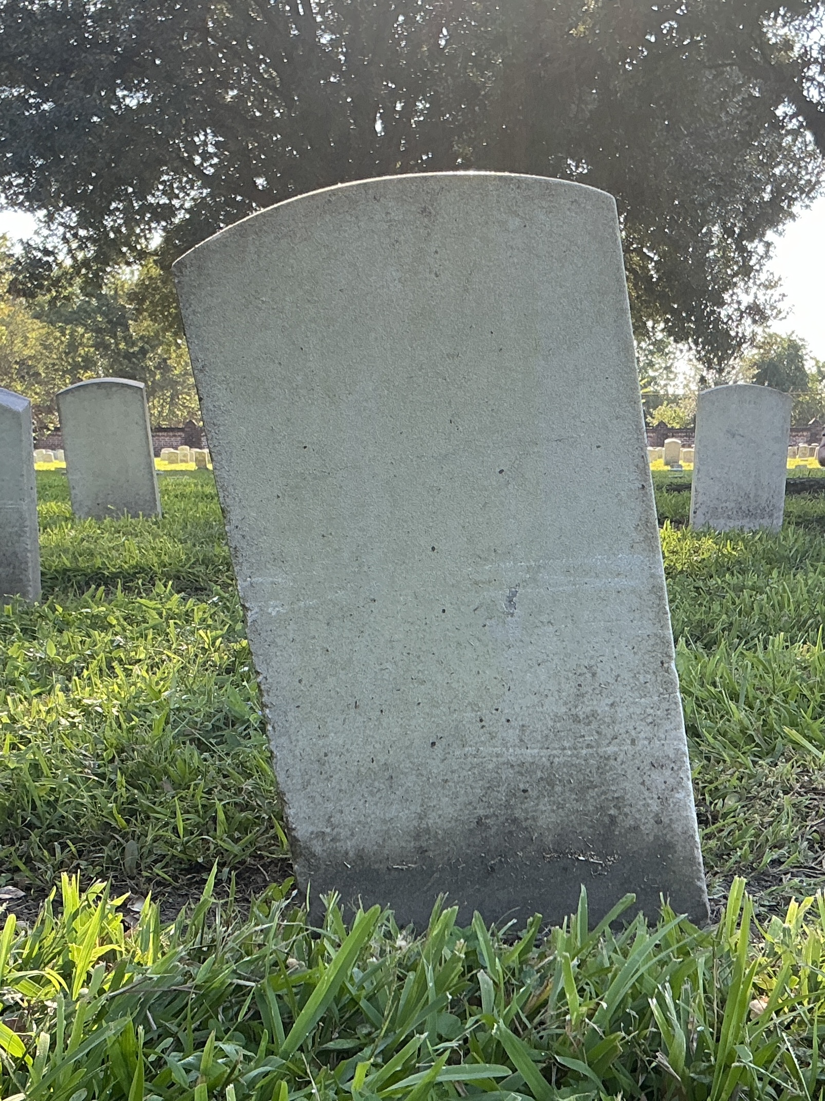 Back of historic upright marble headstone with recessed shield face.