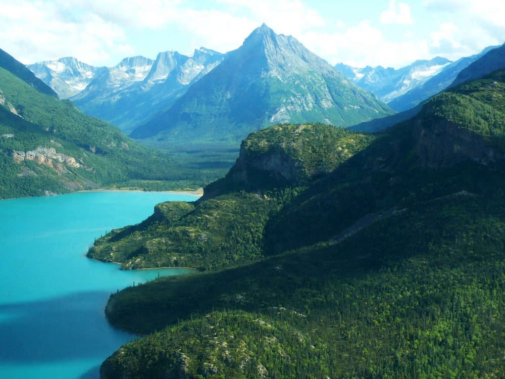 view of a turquoise lake surrounded by forest-covered mountains