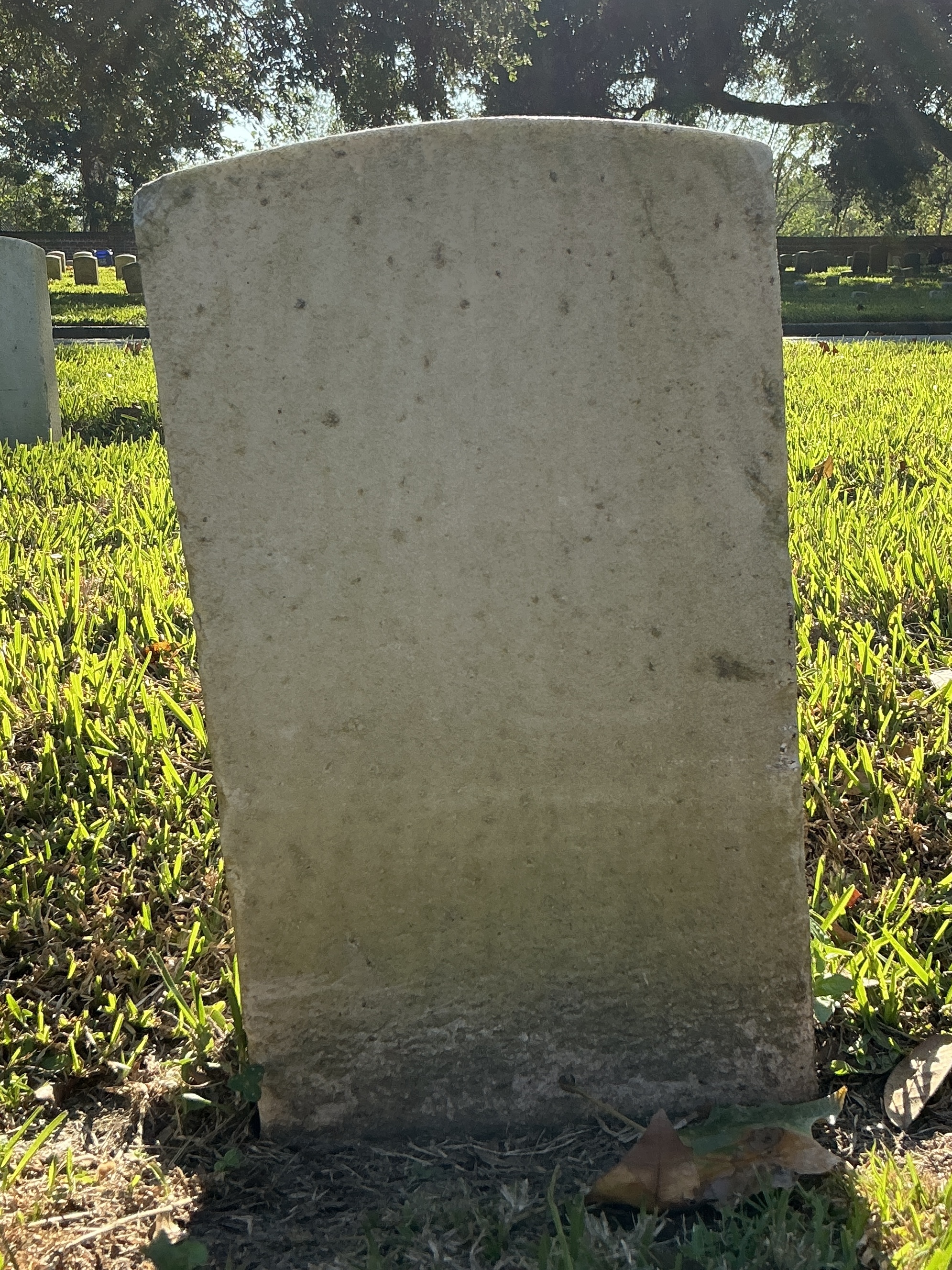 Back of historic upright marble headstone with recessed shield face.