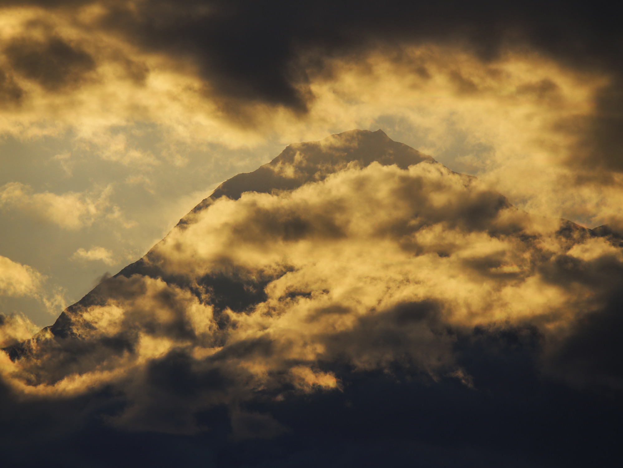 a huge mountain looming out among heavy clouds