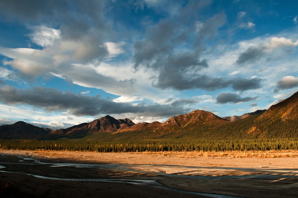 an open plain leading up to mountains, under a partly cloudy sky