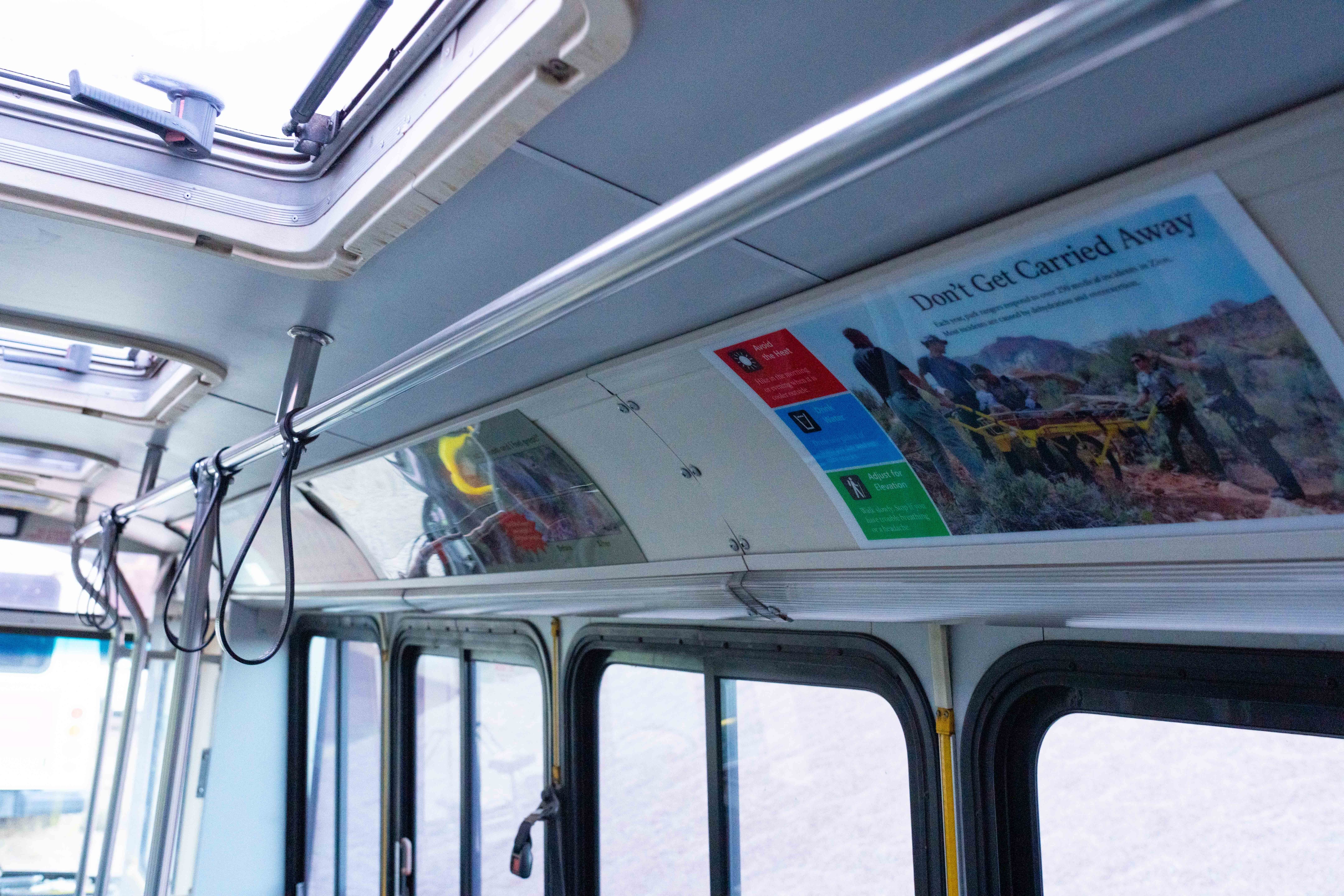 Close up photo of multiple signs that are on display inside the Zion shuttle buses above the windows.