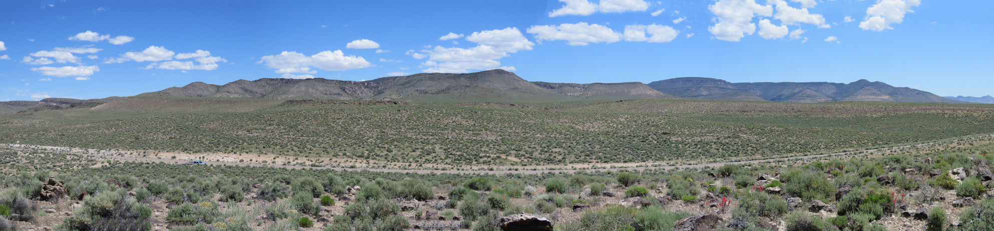 A panorama of Caldera Rim, a part of the Timber Mountain Caldera Complex. The dry landscape is filled with sage and other shrubs.