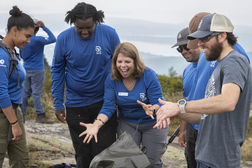 SCA President Lidia Soto-Harmon is cheered on as she places the final bag of soil on top of Sargent Mountain.