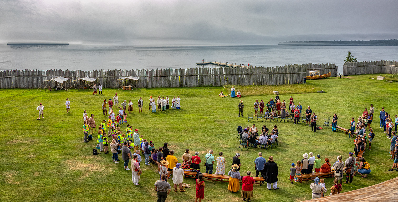 A large crowd of people form a circle watching a drum circle of singers preform on the Great Hall lawn.