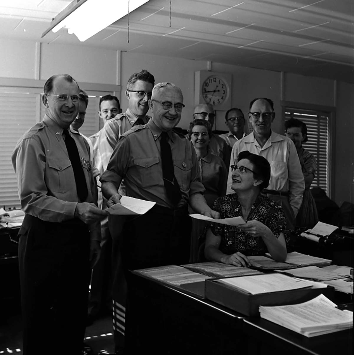 Superintendent Paul R. Franke presenting awards to Ruth Byrd and Carl E. Jepson with members of office staff looking on, headquarters building.