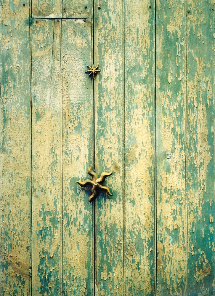 Two bronze plaster stars hanging on a blue green ceiling.