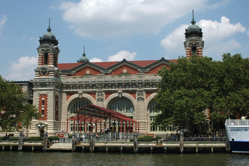 Brick and limestone Beaux-Arts building with prominent modern maroon canopy and cupola-topped towers