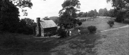 Several people follow the walkway that leads down a slope towards the cabin.