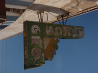 A green sign hanging from the side of a building.