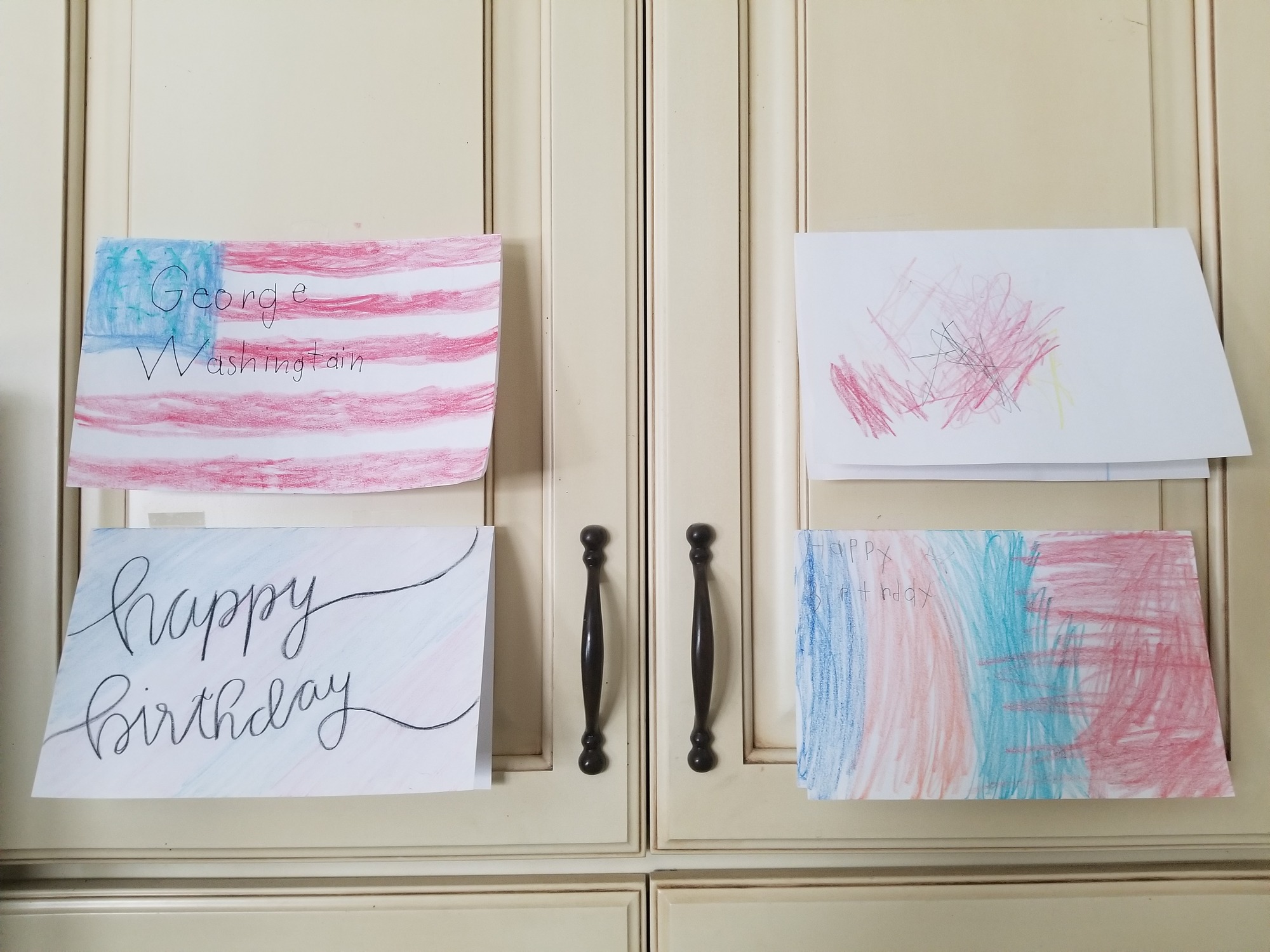 indoors, four handmade cards hung on a cupboard an photographed.
