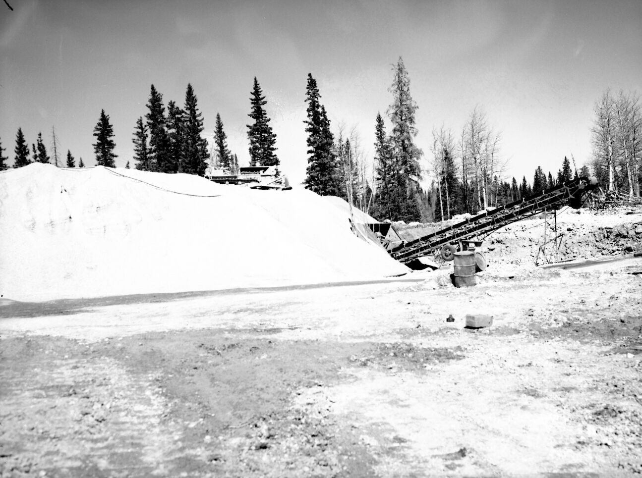 Gravel pit area with conveyor equipment and bulldozer, used for surfacing the rim road. Record of project completion.