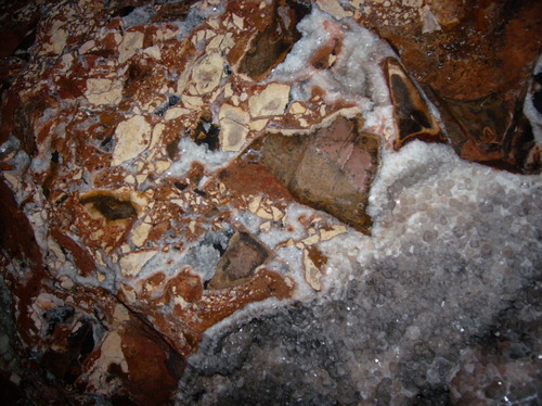 Rock containing angular fragments of red and yellow rocks and calcite crystal
