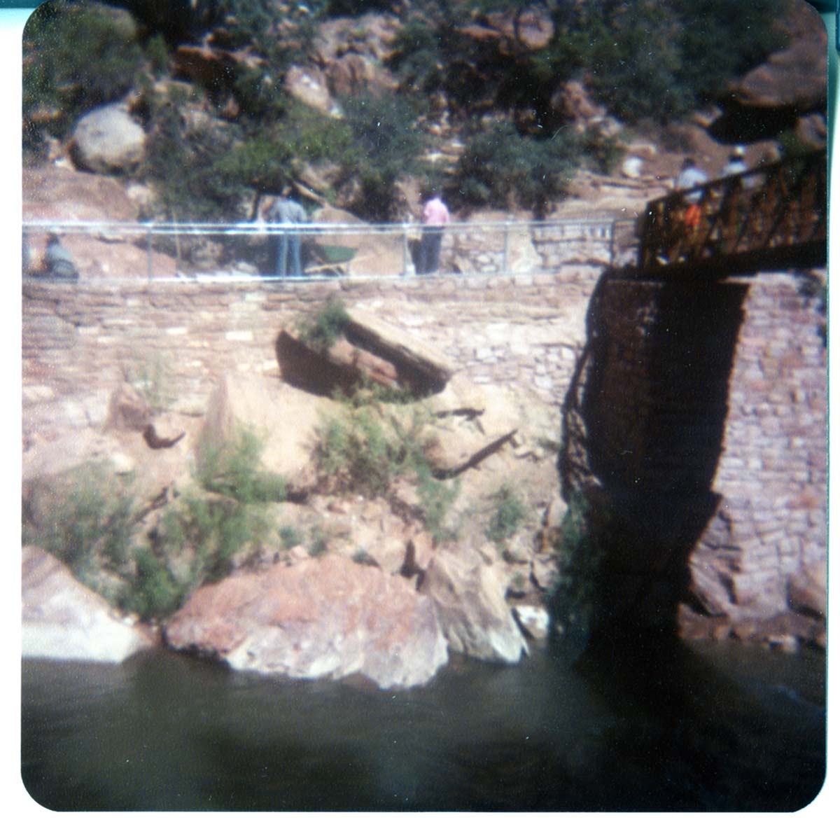 Men working on trail by the new Grotto footbridge. Overview of stone abutment for bridge and trail along Virgin River.
