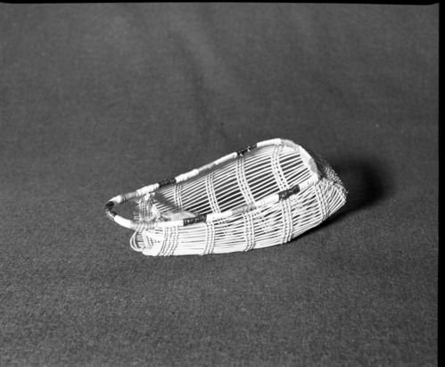 Marie Rozier Collection, Catalog No. 10. Object: Model Yurok cradle. Dimensions: 9 1/2 x 4". Materials: Hazel shoots, conifer root, beargrass, maidenhair fern stem, woodwardia dyed with alder stems. Technology: Plain twined, alternate rows alternate slanted turns with twining. Collection History: Purchased 1964 by Mary Long at Hupa Reservation, Willow Creek, CA. Photographed by Michael Dixon in December 1982. Catalogued by Craig Bates and Barbara Beroza. Yosemite Collections, National Park Service.