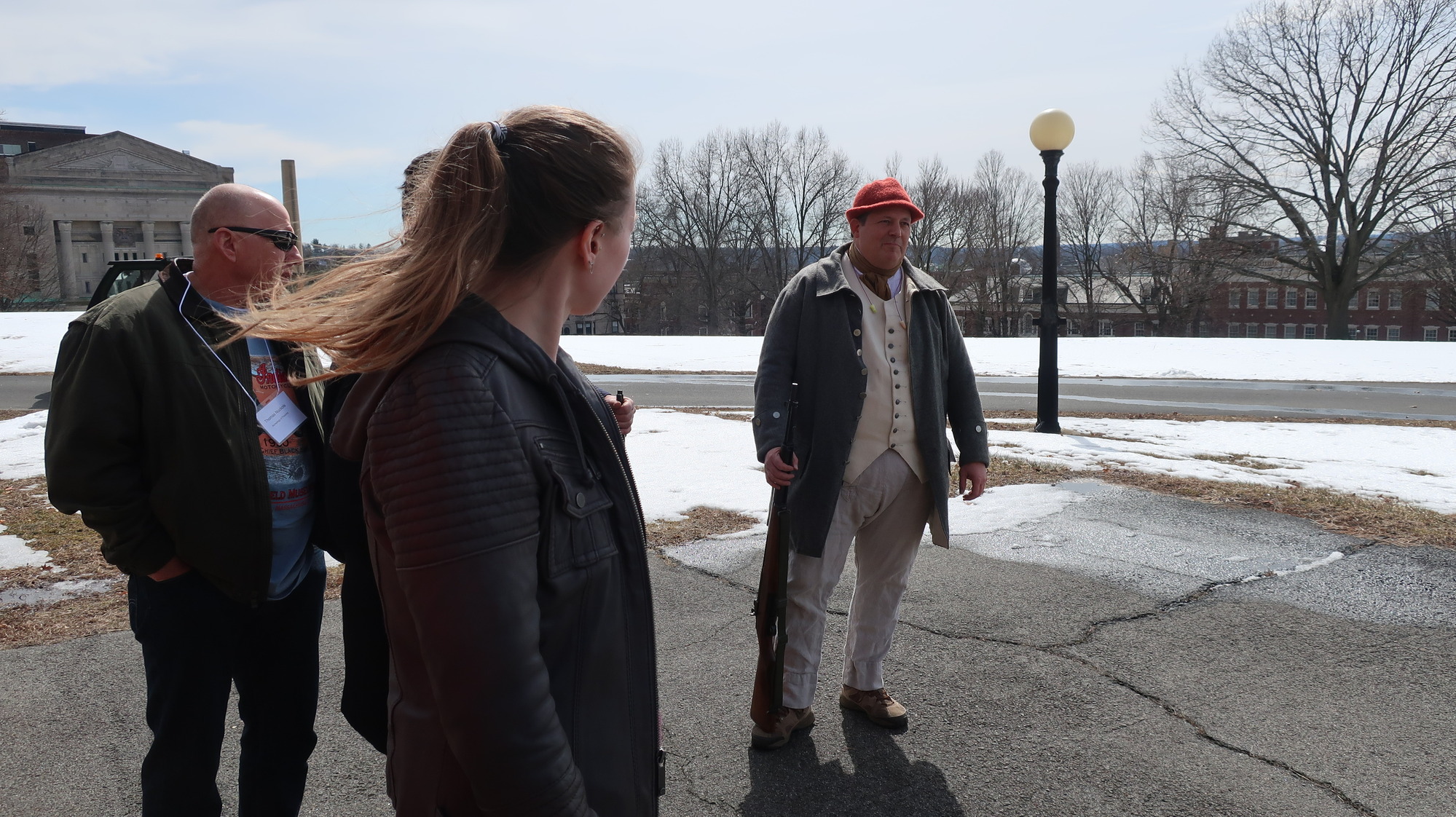 A man explaining range safety to a group of people in a snowy parking lot.