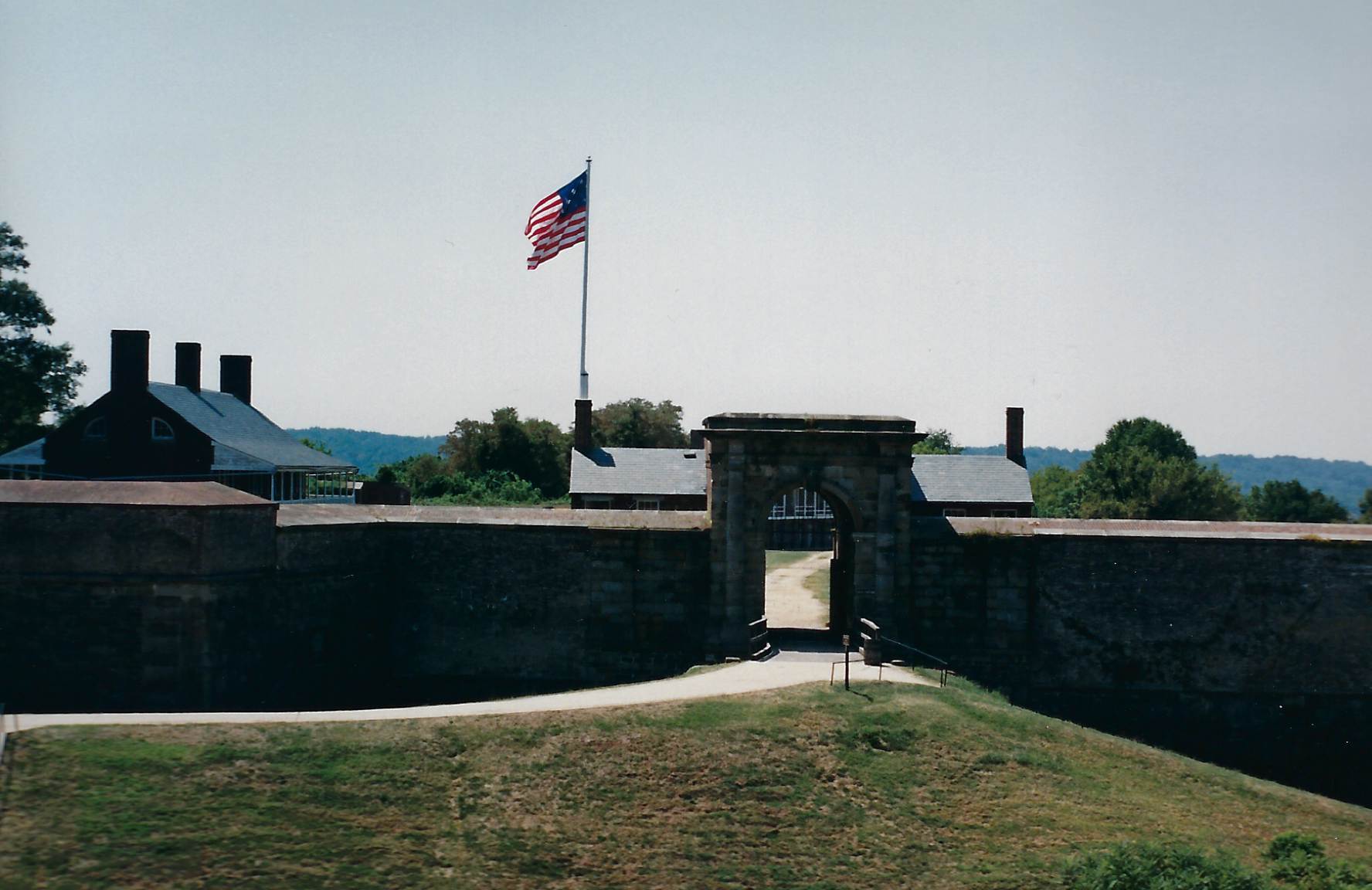 Photo of the fort's front wall, with the entrance doors open.  Large American flag is raised over the fort.