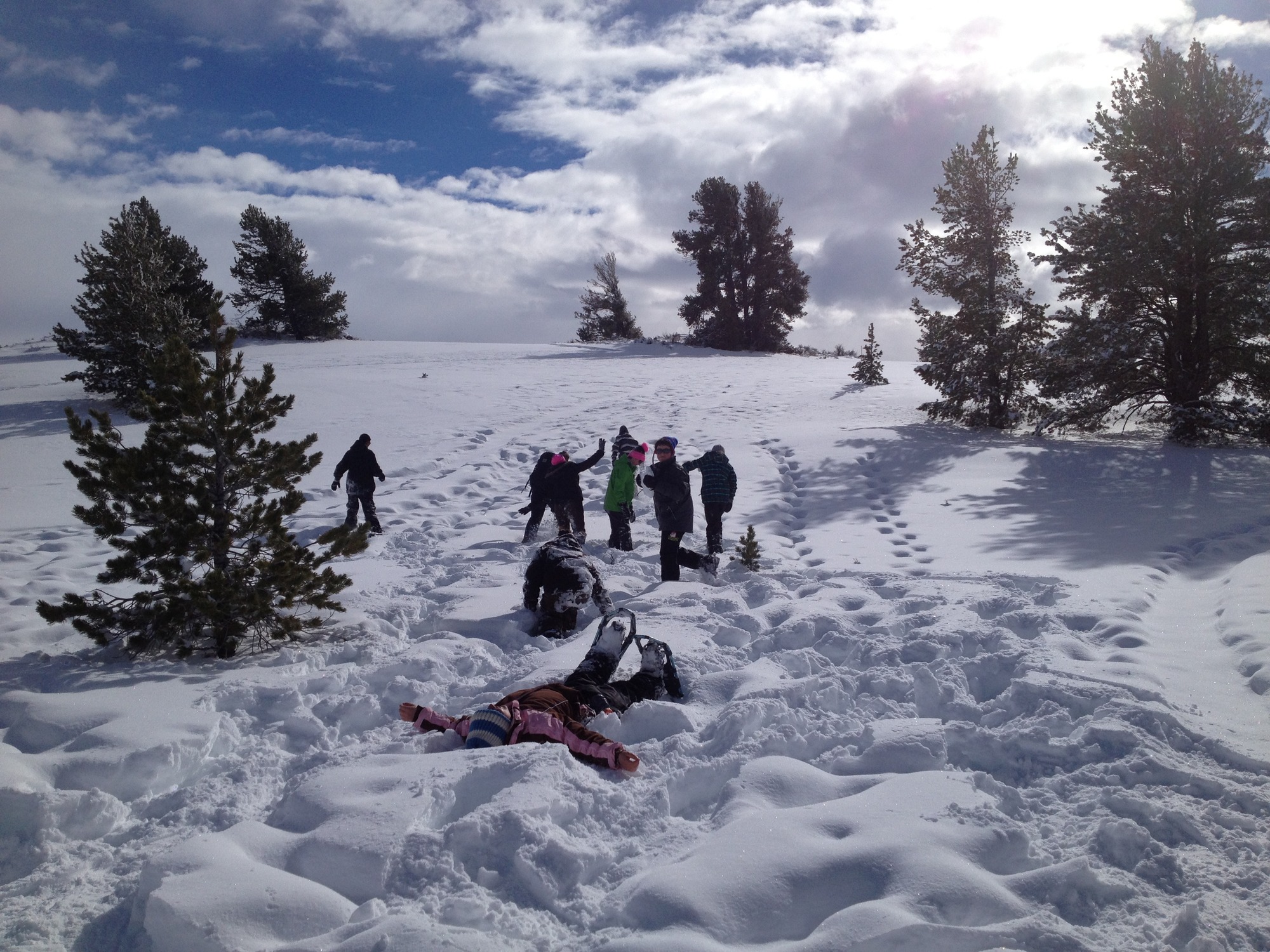 several children on snowshoes, one lying in the snow making snow angels
